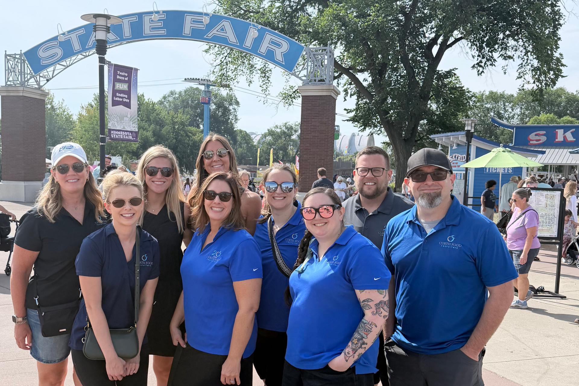 Curtis Food Recruiters team posing under the Minnesota State Fair entrance arch.